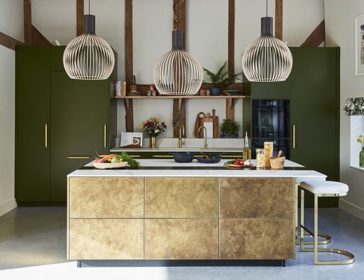 a Sola Kitchens design featuring a white and brass kitchen island with three pendant lights above it