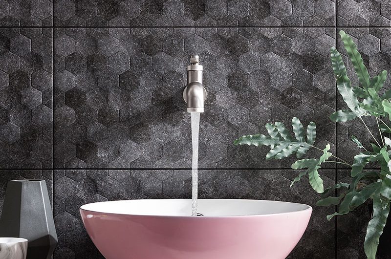 Textured black wall tiles with pink basin on marble countertop