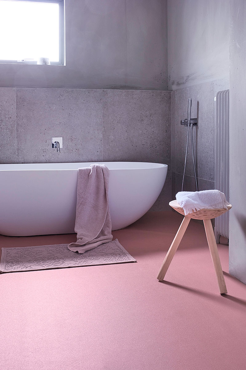 Family bathroom with pink vinyl flooring and grey cement walls