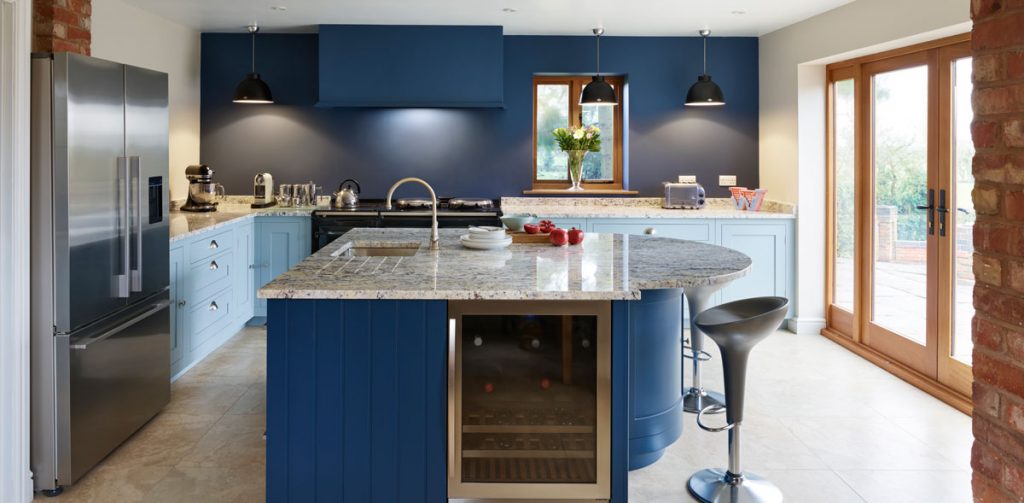a blue shaker-style kitchen painted royal blue, with a kitchen island with grey stools around it