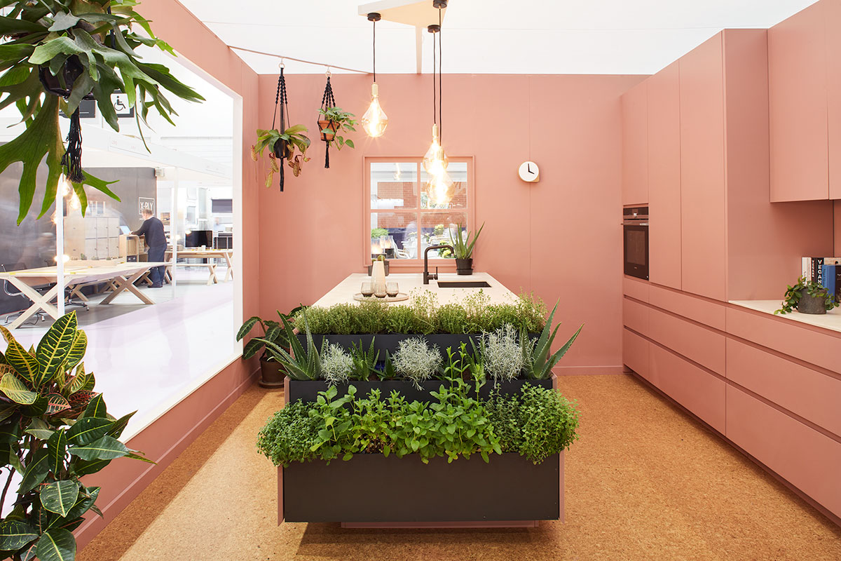 Eco-friendly kitchen in pink with island featuring planting baskets
