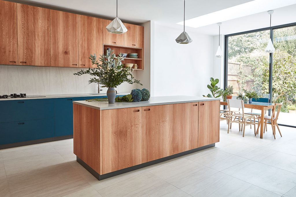 a warm wood island with a quartz worktop and wood cabinetry with modern grey pendant lights to illustrate a feature on kitchen must-haves for entertaining