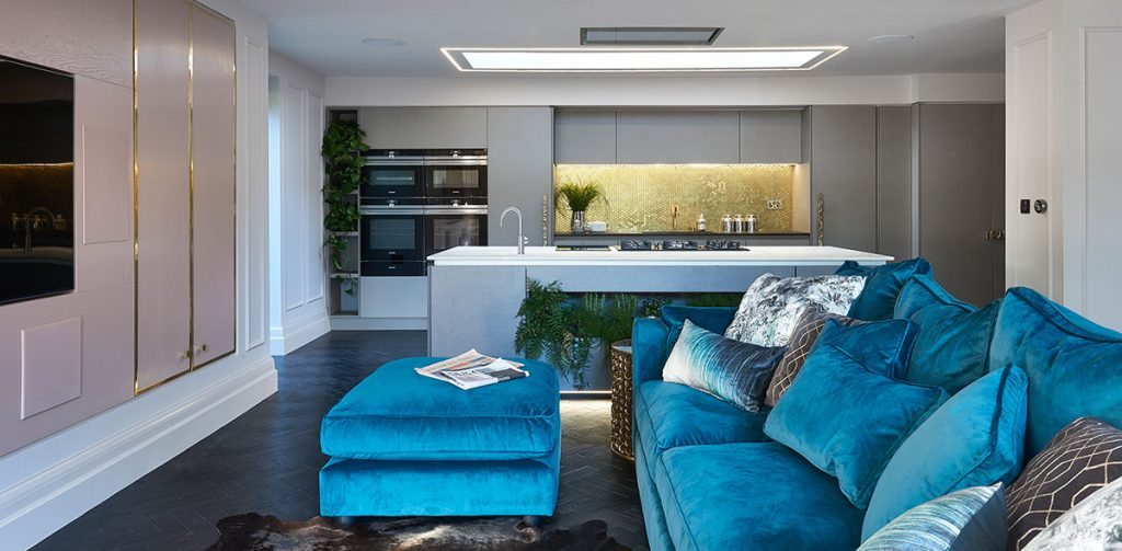 a blue sofa and pouffe in a kitchen with a white and grey kitchen island and cabinetry to illustrate a feature on kitchen must-haves for entertaining 