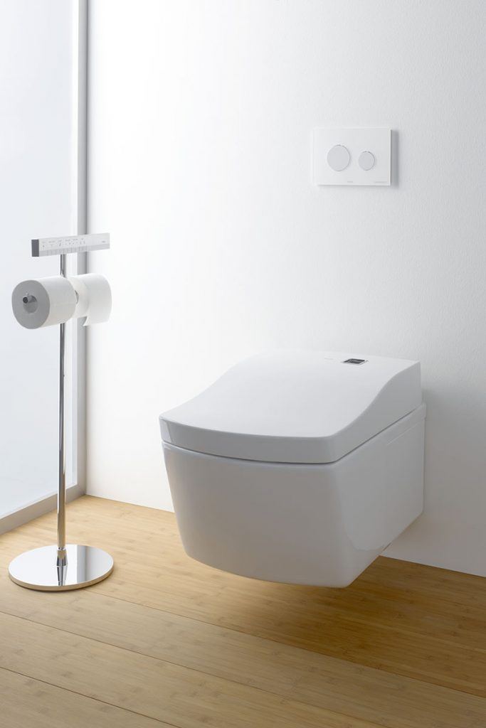 a dual flush toilet next to a toilet roll holder