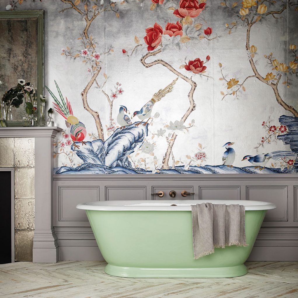 a green freestanding tub next to floral wallpaper