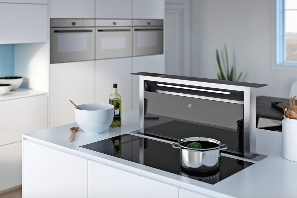 the v‐zug downdraft extractor next to a black hob with a steel pan on it