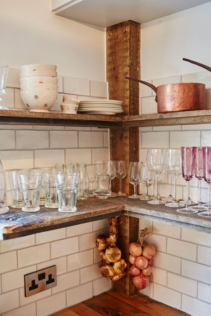 wood open shelving showcasing a range of glasses, pans and crockery