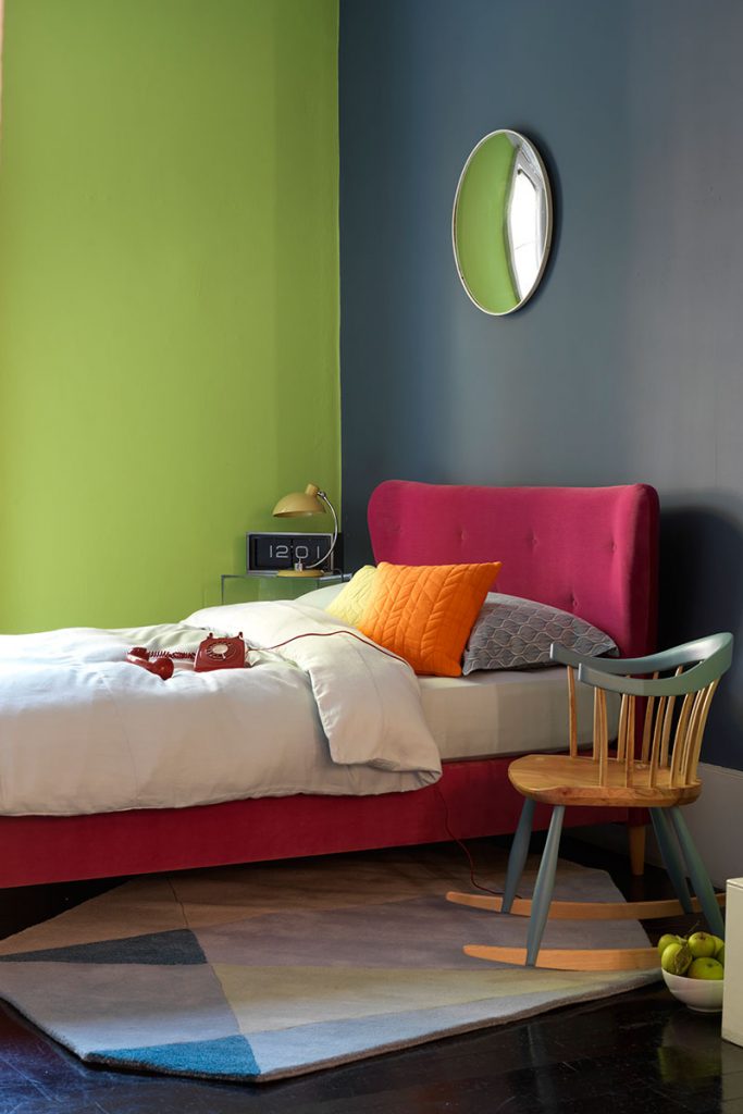 pink headboard in front of green wall 
