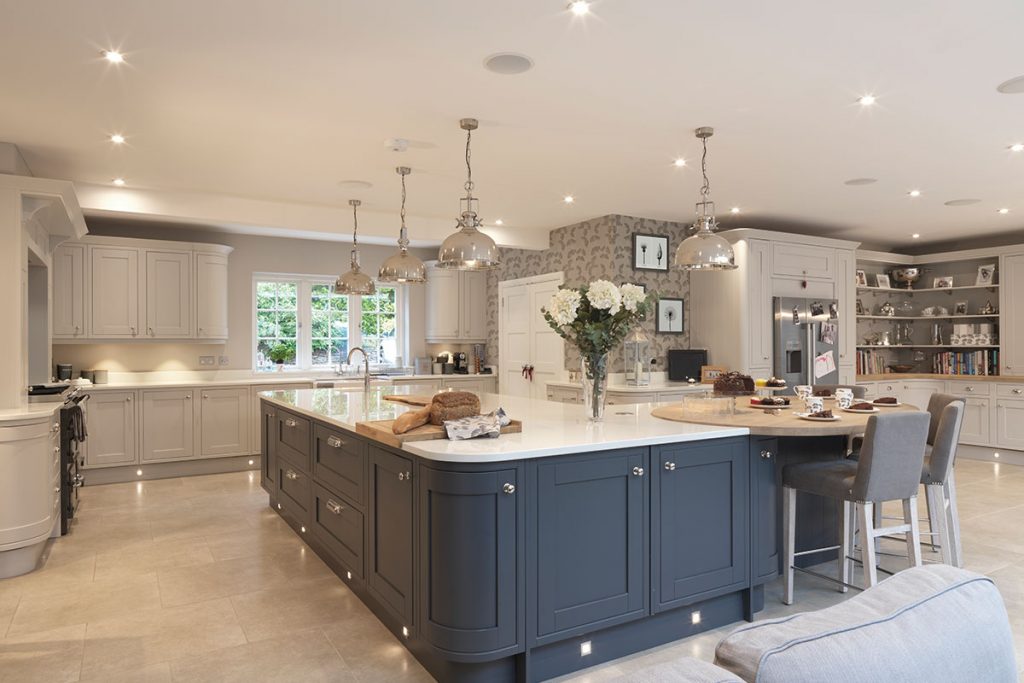 a very large blue shaker-style kitchen with navy and grey cabinetry and silver pendant lights