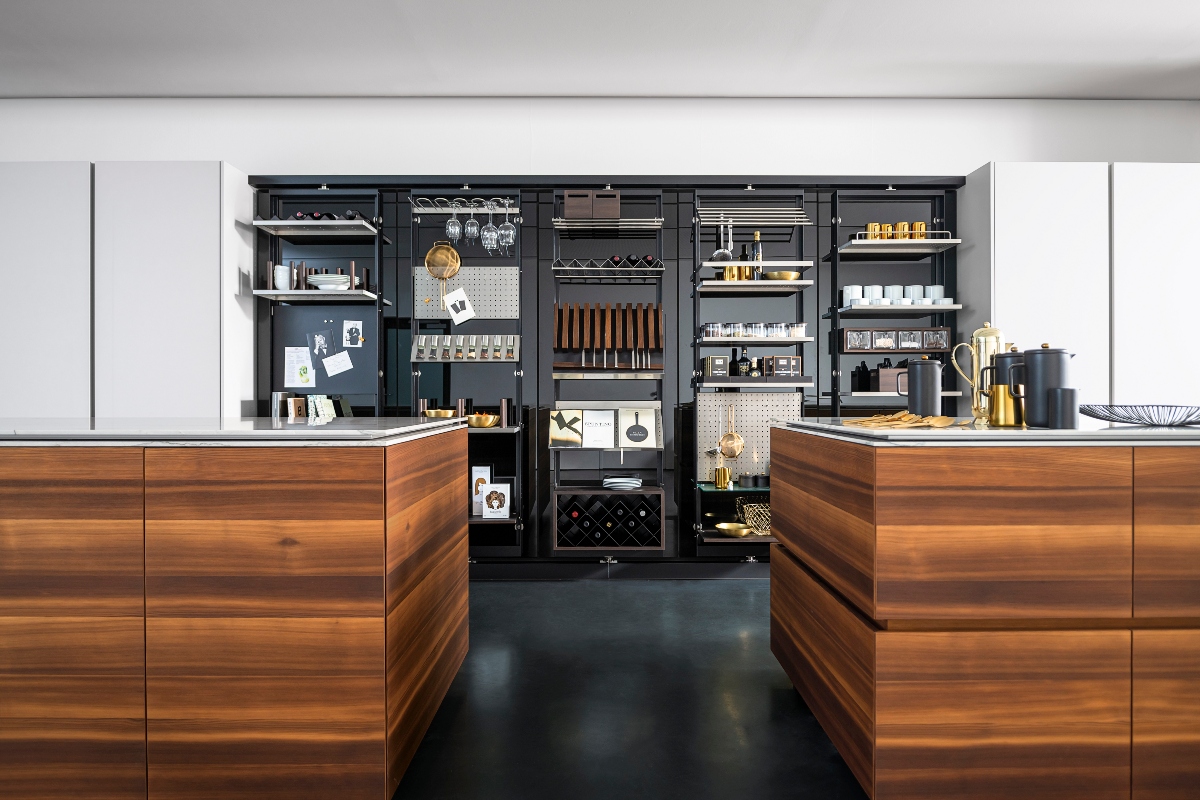 a black and walnut kitchen with lots of storage holding crockery, cutlery, mugs, glasses and utensils