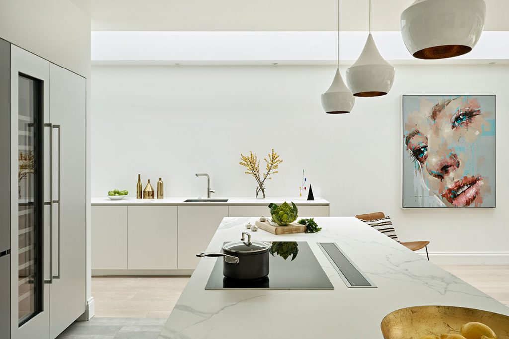 a white kitchen with three white pendant lights hanging above a marble kitchen island