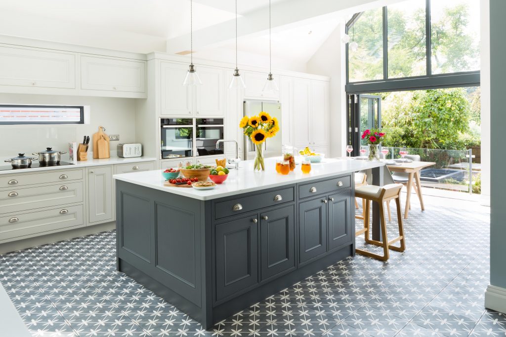 a light and airy kitchen extension featuring anthracite cabinetry under a white kitchen island, accessorised with a large bunch of sunflowers and various foodstuffs, illustrating how to make your kitchen bigger