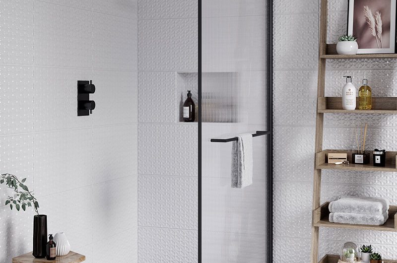 a bathroom design featuring a fluted glass shower enclosure with matt black fixings, floral monochrome floor tiles and a ladder shelf