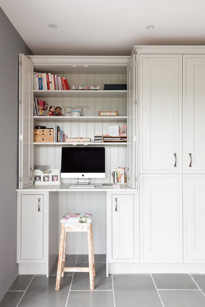 a home office hidden behind white Shaker cabinetry