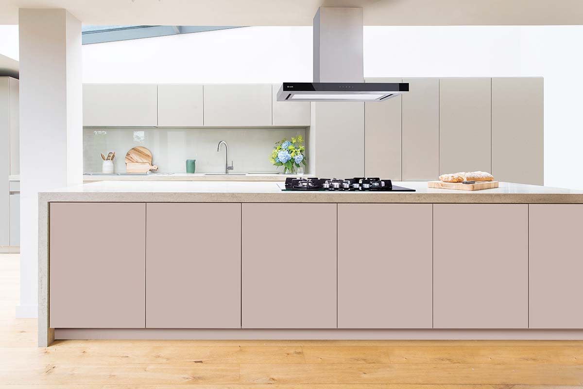 an extractor hood above a White island in a pale pink handleless kitchen