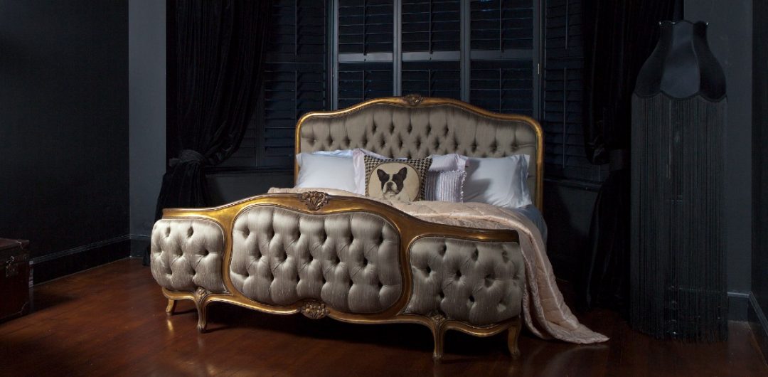 a gold four-poster Chesterfield bed from the French Bedroom Company on a dark red carpet