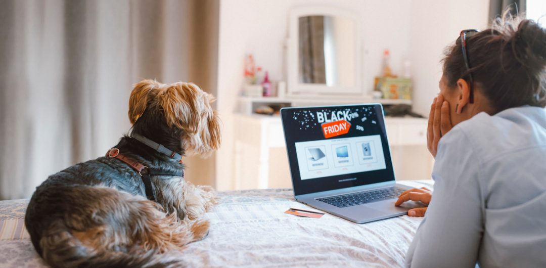 a dog and a woman on a laptop wondering how to get the best Black Friday deals
