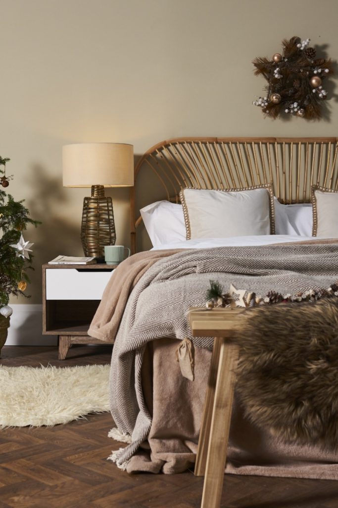 Neutral bedroom with throws, bedside lamp, foliage and wreath