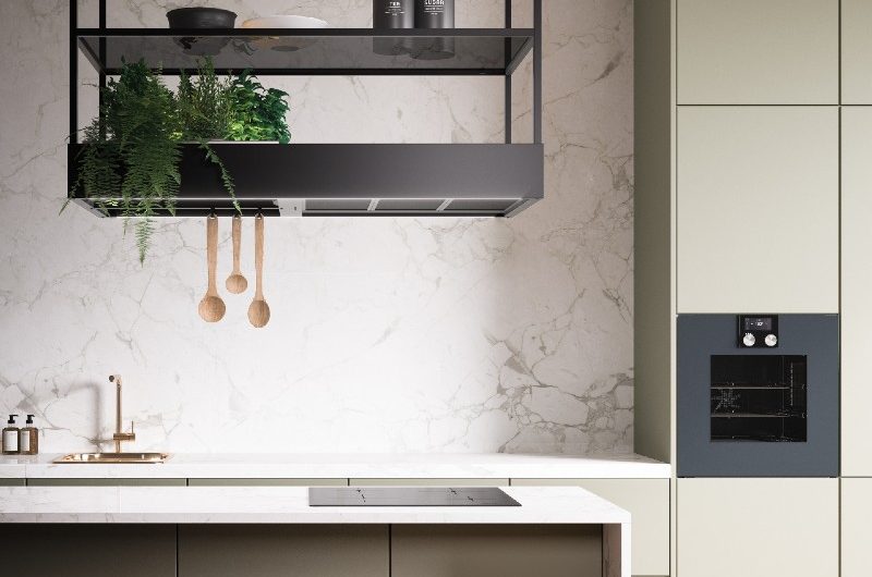 the Falmec Spazio hood kitchen appliance in an olive green kitchen with a marble cplashback