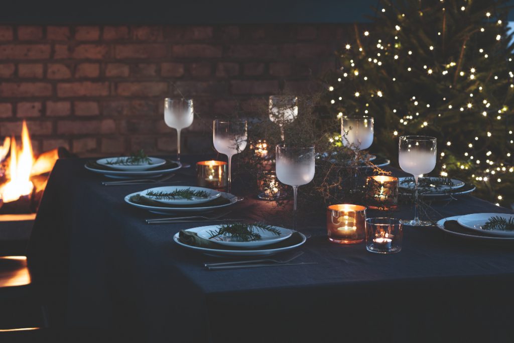 Frosted wine glasses and white plates, tealights and small pine brances