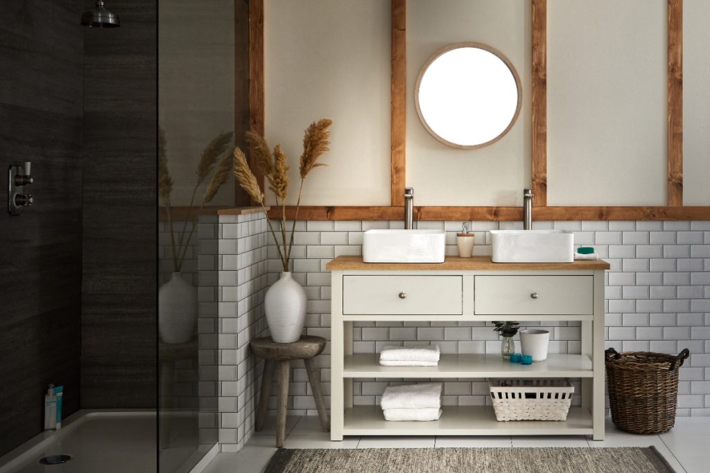 a modern rustic bathroom featuring a large two-drawer vanity unit with two basins under a round wooden mirror