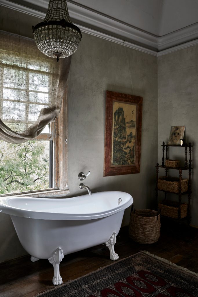 a freestanding white roll top bath with claw feet in a room full of antiques