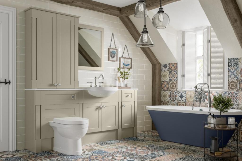 a navy blue freestanding bath surrounded by floral wall tiles, beige metro brick tiles, beige Shaker wall panelling and a white toilet and basin
