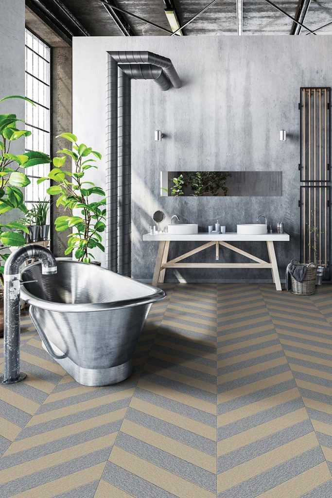 an industrial room featuring brushed metal tiles in a chevron pattern, a silver roll top tub, a double basin and lots of green plants