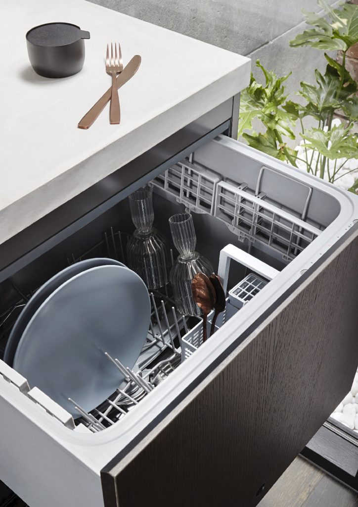 a DishDrawer dishwasher with a wooden front panel and crockery and glasses inside