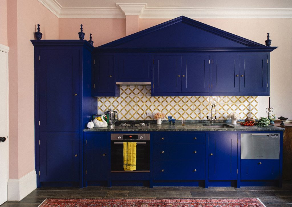 a small kitchen painted in the colour royal blue with yellow wall tiles and powder pink walls