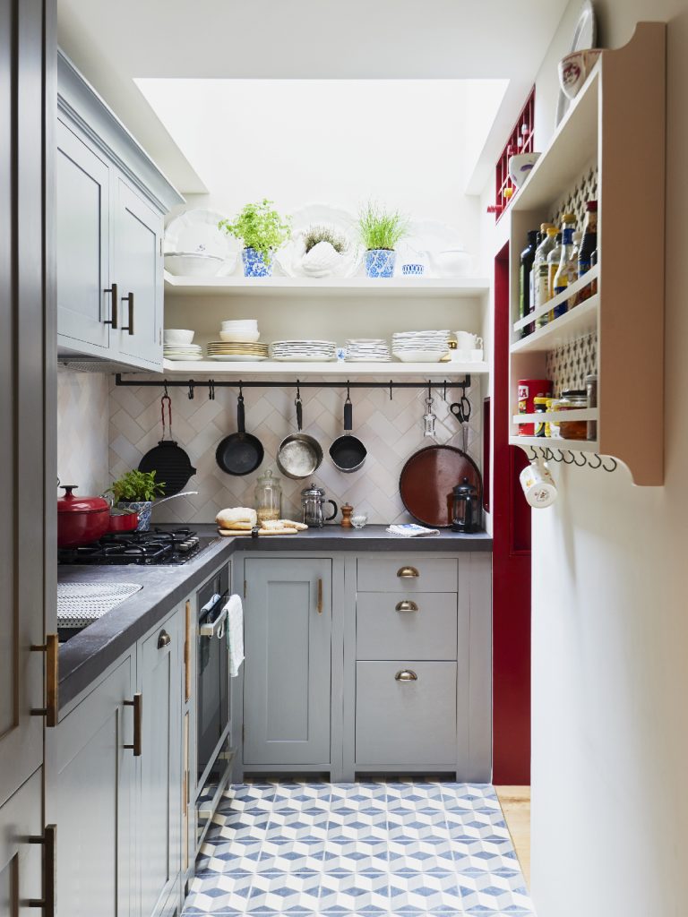 The Suffolk design in the colour Fog, featuring open shelving for pans and crockery and grey cabinetry with brass handles