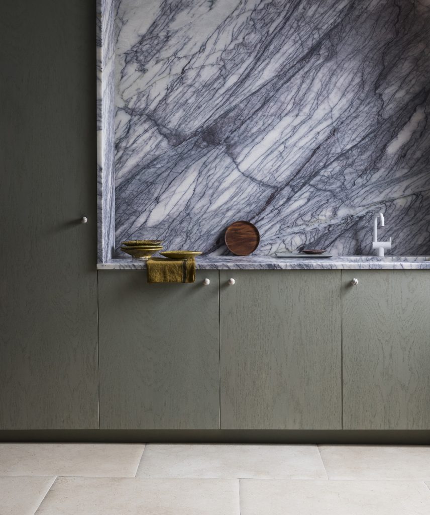 a small kitchen with a blue marble splashback and olive green cabinetry