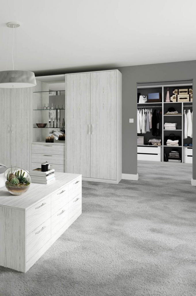 a large walk-in wardrobe with ash white doors and dividers, featuring lots of clothes including shirts and t-shirts hanging up, for a feature on how to design a dressing room