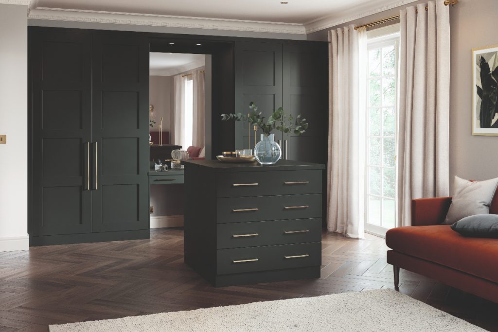 a bespoke built-in wardrobe with a mirror in the middle, dark green Shaker cabinetry and brass handles for a feature on how to design a dressing room