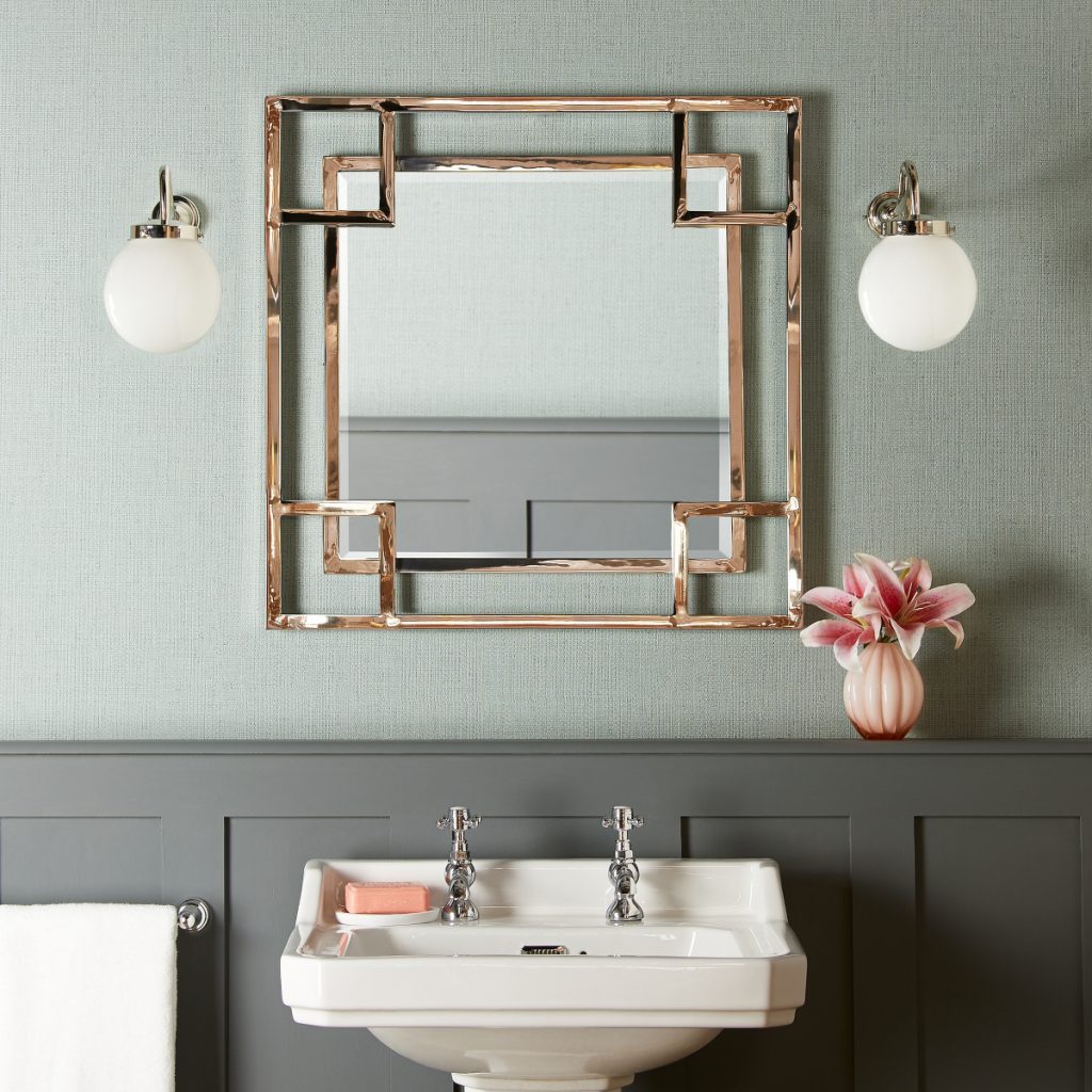 a Daffings mirror in gold geometric patterns above a pedestal basin