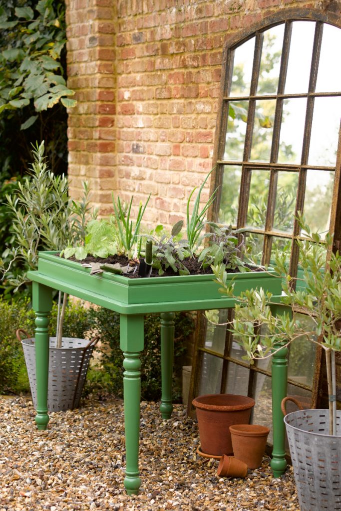 an outdoor table with plants on painted in the colour Superdec Mid Green