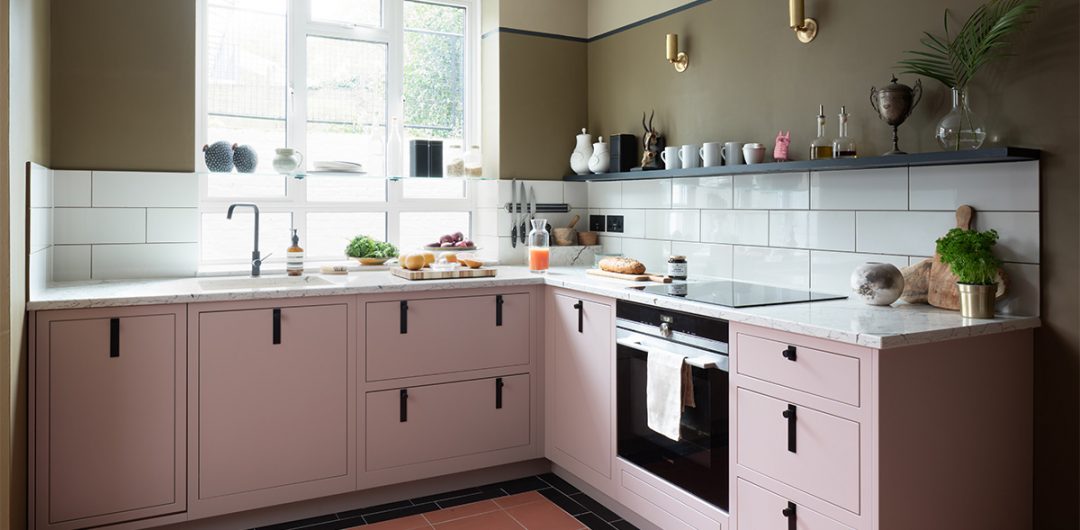 a small kitchen with pale pink and black cabinetry