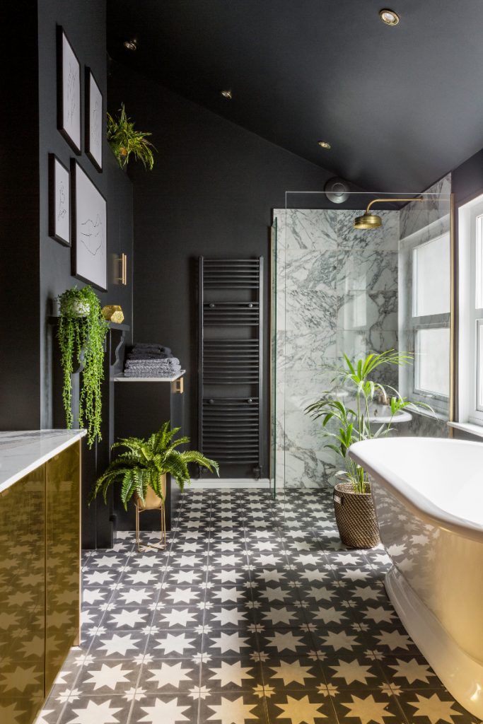 a black Art Deco bathroom with monochrome star tiles and a white freestanding bath
