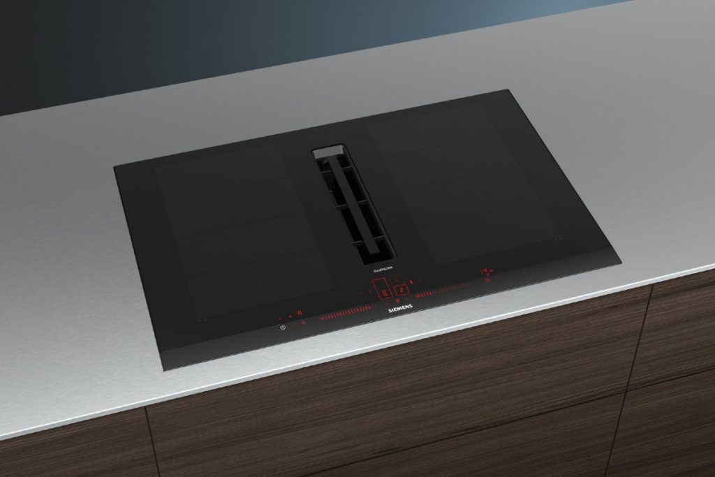a hob with extractor in a kitchens set into a white worktop with dark walnut cabinetry beneath it
