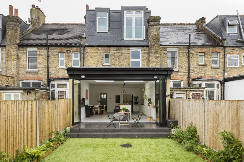 a single-storey rear build with bi-fold doors and skylights in front of a lawn