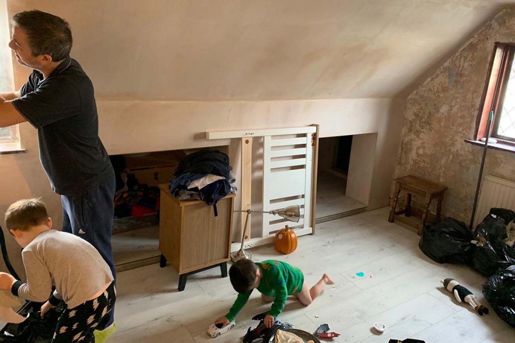 a family decorating a large room with bare floorboards