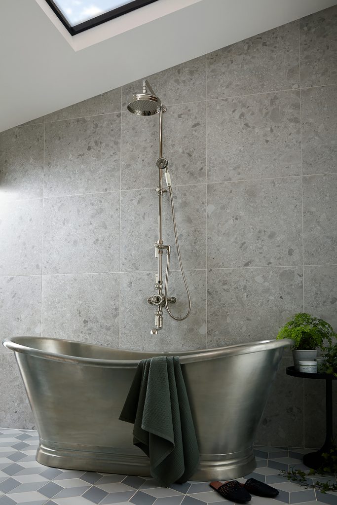 a tin boat bath in a gold sheen with a brass shower and geometrical floor tiles