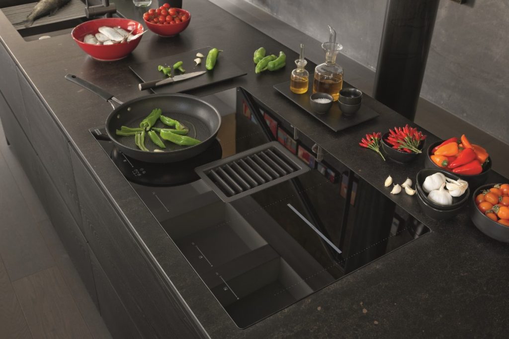 The Franke Mythos 2gether cooktop with many different bowls of foodstuffs around it such as garlic, red peppers and green peppers