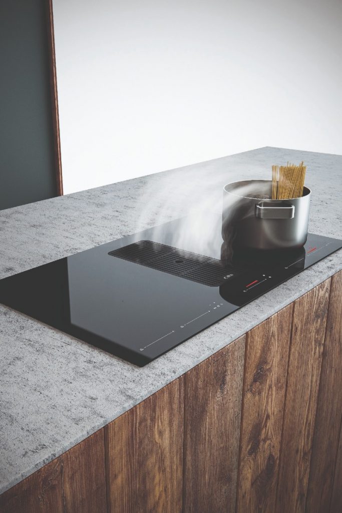 the CDA HNE8 cooktop set into a stone worktop with a steaming stainless steel pan on top of it containing spaghetti