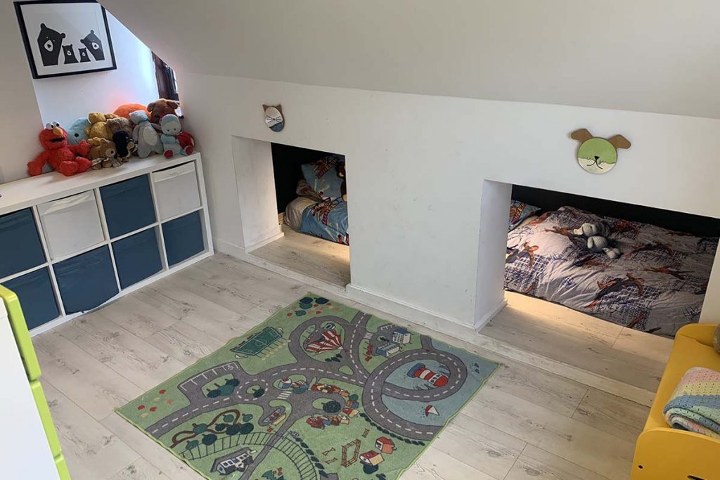 a kids bedroom renovation featuring white and navy storage cubes, beds in a den and a rug on the floor