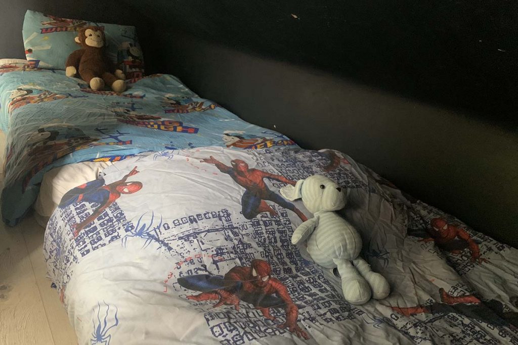 two beds with superhero duvet covers and cuddly toys in a den
