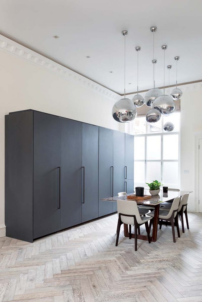 an open plan room with pull doors in a matt black finish and a dining table with six beige chairs