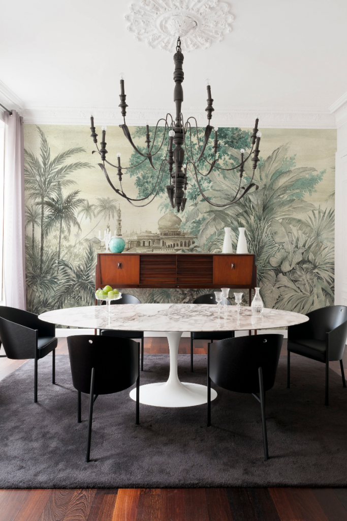 chinoiserie wallpaper as a feature wall behind a round white dining table with six black chairs