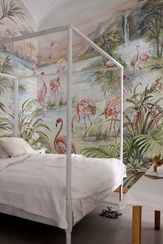 Flamingo chinoiserie wallpaper as a feature wall behind a white four-poster bed