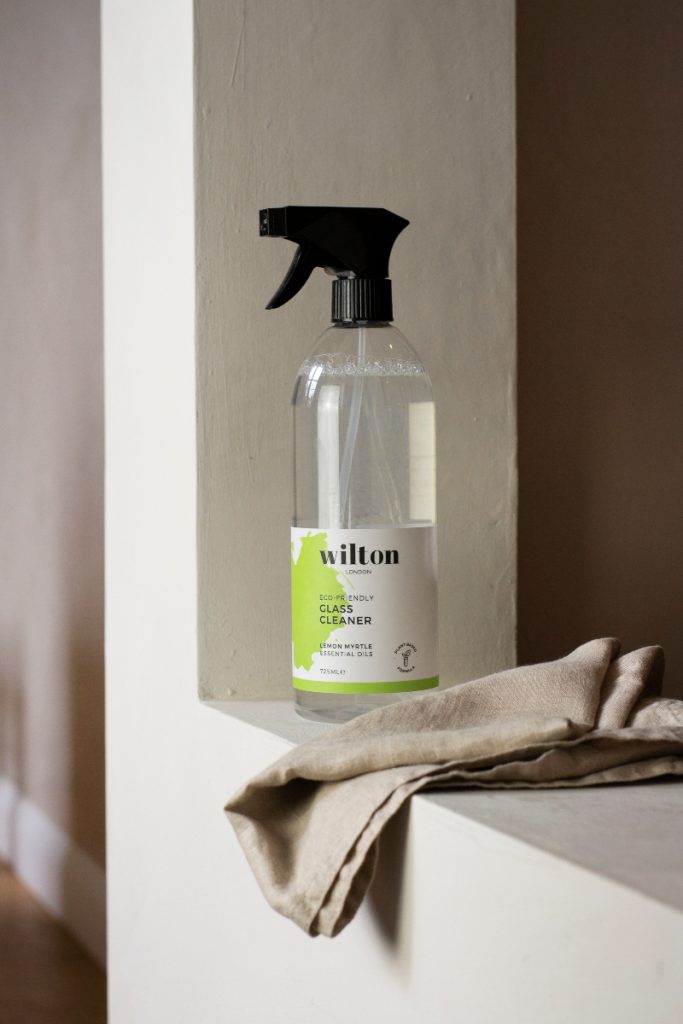a bottle of Wilton glass cleaner for sustainable cleaning, next to a cloth